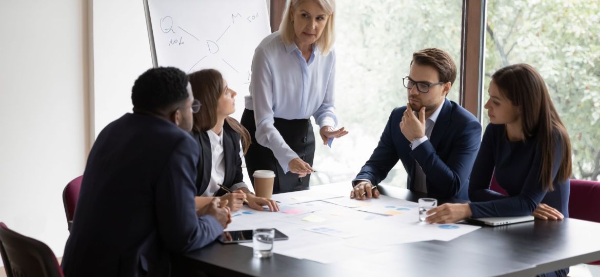 Focused female boss brainstorm with diverse colleagues at briefing
