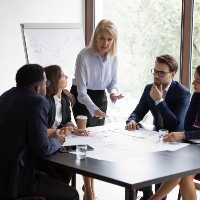 Focused female boss brainstorm with diverse colleagues at briefing